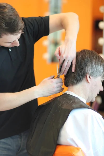 Muž zastřihne vlasy v holičství. Master mladé kadeřnice. Zaměřit se na šedivé vlasy — Stock fotografie
