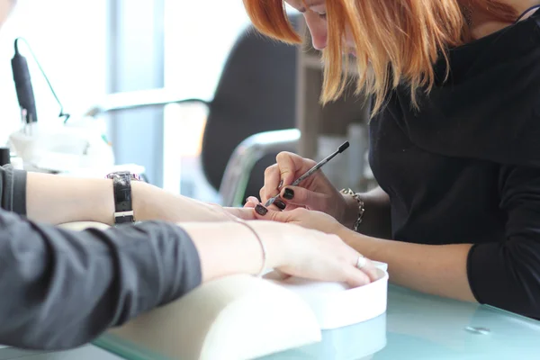 Mujer en salón de uñas recibiendo manicura por esteticista. Mujer recibiendo manicura en el salón de belleza —  Fotos de Stock