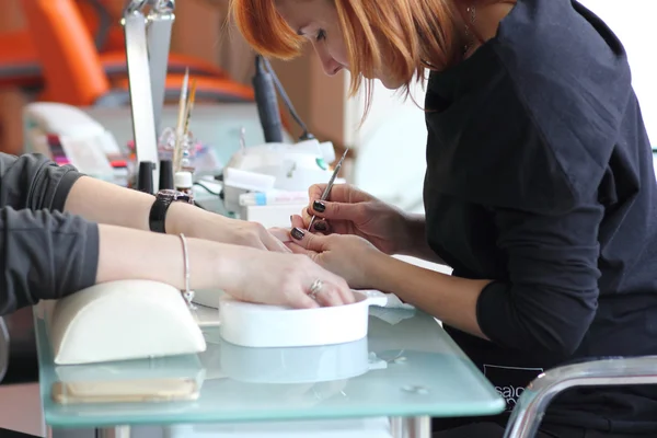 Mujer en salón de uñas recibiendo manicura por esteticista. Mujer recibiendo manicura en el salón de belleza —  Fotos de Stock