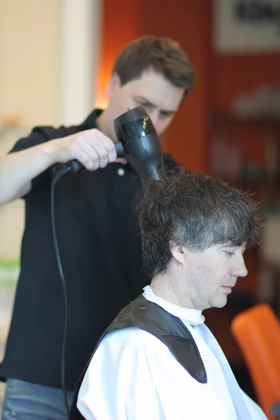 Un homme coupe des cheveux dans un salon de coiffure. Master jeune styliste.Focus sur les cheveux gris Photos De Stock Libres De Droits