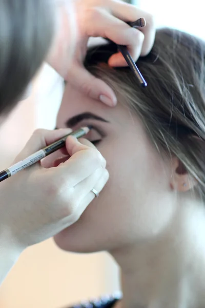 Joven maestro de maquillaje mirando el maquillaje de la mujer en el salón — Foto de Stock