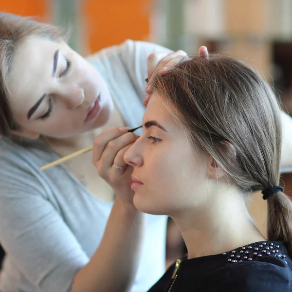 Jeune maquillage maître regardant le maquillage de la femme dans le salon — Photo