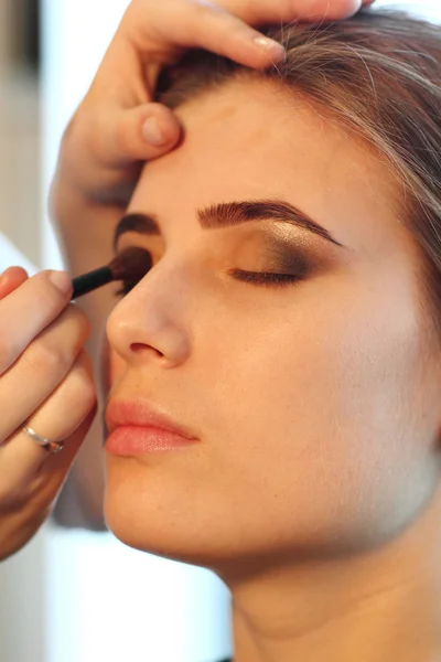 Jeune maquillage maître regardant le maquillage de la femme dans le salon Images De Stock Libres De Droits