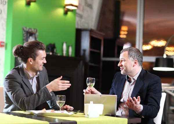 Deux hommes d'affaires souriants mangent au restaurant — Photo