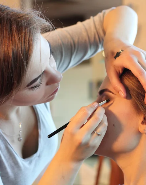 Mujer joven estilista haciendo maquillaje hermosa chica en salón de belleza — Foto de Stock