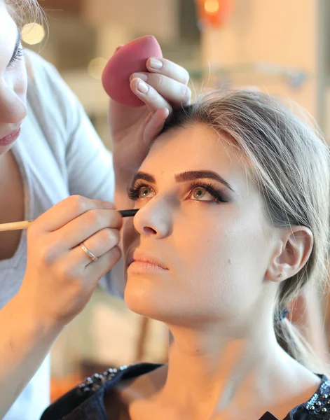 Mujer joven estilista haciendo maquillaje hermosa chica en salón de belleza — Foto de Stock