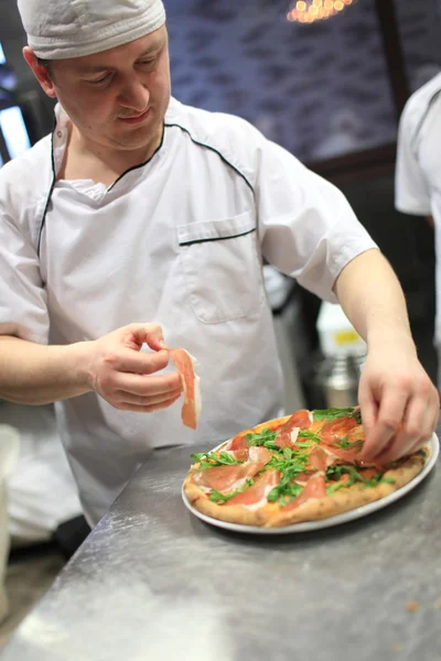 Bucătar brutar în uniformă albă făcând pizza la bucătărie . — Fotografie, imagine de stoc