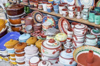 Renkli boyanmış kil kapları, Gyuvech, bir rafta güzelce sergilenmiş. İşçilik ve geleneksel tasarım odaklı