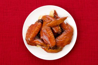 Teriyaki tavuk kanatları kırmızı masa örtüsünde bir tabakta