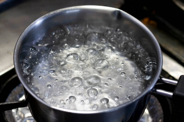 Boiling water in stainless pan in kitchen