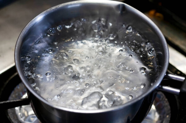 Boiling water in stainless pan in kitchen
