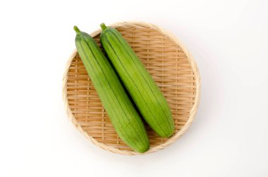 Taze yeşil sünger kabağı ya da beyaz arka planda bambu elek üzerinde luffa.