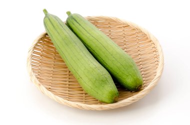 Taze yeşil sünger kabağı ya da beyaz arka planda bambu elek üzerinde luffa.