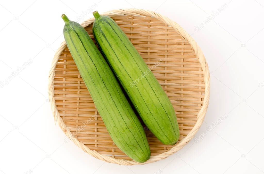 fresh green sponge gourd or luffa on a bamboo sieve on white background