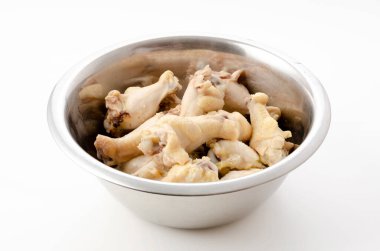 Beyaz arka planda paslanmaz çelik bir kasede haşlanmış tavuk..