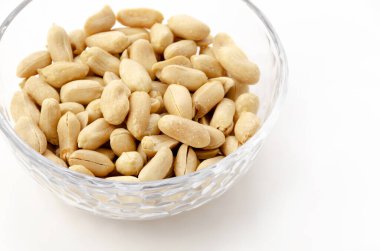 Beyaz arka planda şeffaf cam bir kasede kavrulmuş tuzlu fıstık.