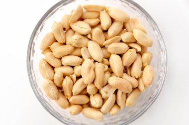 Beyaz arka planda şeffaf bir tencere içinde kavrulmuş tuzlu fıstık.