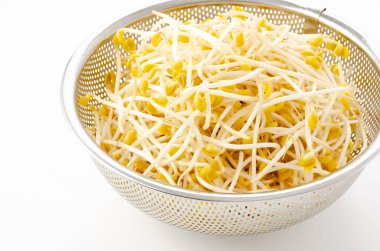 Beyaz arka planda paslanmaz çelik kevaşe içinde taze soya fasulyesi filizleri.