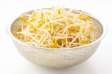 Beyaz arka planda paslanmaz çelik kevaşe içinde taze soya fasulyesi filizleri.