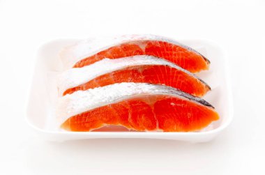 Beyaz arka planda köpük tepside çiğ fileto alabalığı.