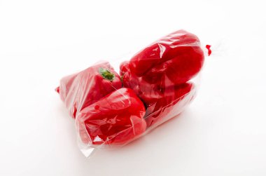 Beyaz arka planda plastik poşette kırmızı dolma biber.