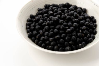 Beyaz arkaplanda pişmemiş siyah fasulye.