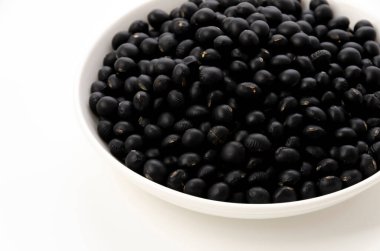 Beyaz arkaplanda pişmemiş siyah fasulye.