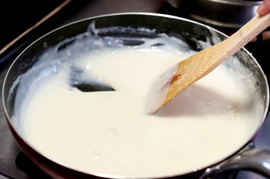 Beşamel. Kremalı sosu ahşap bir spatulayla tavada karıştır.