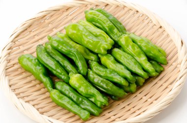 Beyaz arka planda bambu elek üzerinde Shishito yeşil biberi