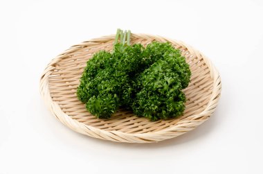 Beyaz arka planda bambu elek üzerine taze kıvırcık maydanoz.