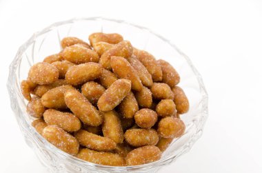 Beyaz arka planda cam kasede kavrulmuş fıstık.