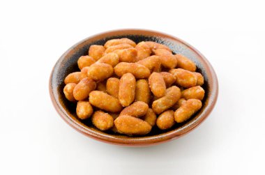 Beyaz arka planda siyah bir tabakta kavrulmuş fıstık.