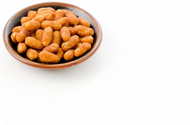 Beyaz arka planda siyah bir tabakta kavrulmuş fıstık.