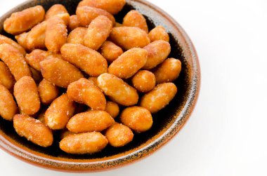 Beyaz arka planda siyah bir tabakta kavrulmuş fıstık.