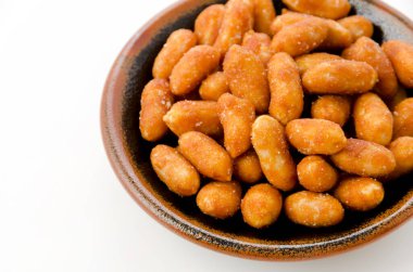 Beyaz arka planda siyah bir tabakta kavrulmuş fıstık.