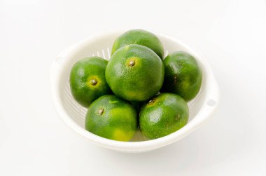 Citrus unshiu, mandarin satsuma portakalı ve beyaz arka planda plastik kevgir.