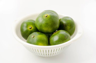 Citrus unshiu, mandarin satsuma portakalı ve beyaz arka planda plastik kevgir.