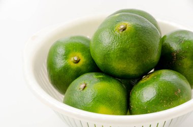 Citrus unshiu, mandarin satsuma portakalı ve beyaz arka planda plastik kevgir.