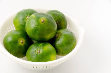 Citrus unshiu, mandarin satsuma portakalı ve beyaz arka planda plastik kevgir.