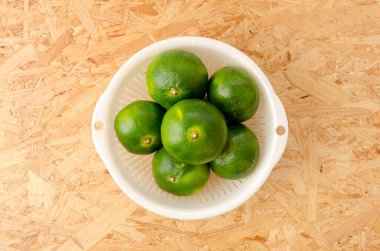 Citrus unshiu, mandarin satsuma portakalı, kontrplak tahta arka planda plastik kevgir.