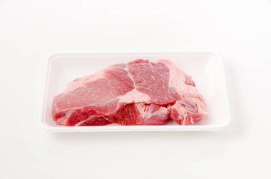 Beyaz arka planda köpük tepside çiğ domuz eti