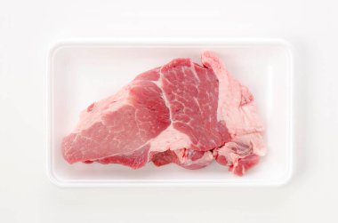 Beyaz arka planda köpük tepside çiğ domuz eti