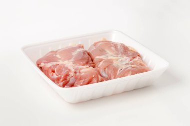 Çiğ tavuk eti beyaz arka planda köpük tepside.