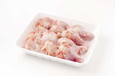 Beyaz arka planda köpük tepside çiğ tavuk kanadı.