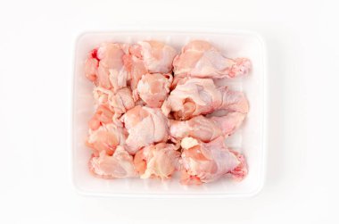 Beyaz arka planda köpük tepside çiğ tavuk kanadı.