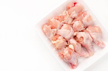 Beyaz arka planda köpük tepside çiğ tavuk kanadı.