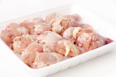 Beyaz arka planda köpük tepside çiğ tavuk kanadı.