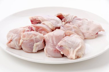 Beyaz arka planda beyaz tabakta çiğ tavuk eti.
