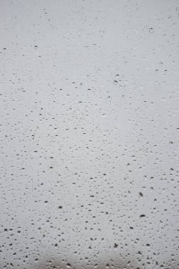 Su damlaları ile ıslak cam pencere açık gri yağmurlu arka plan, yakın plan