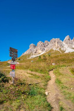 Pizes da Cir 'in sihirli Dolomite tepeleri, mavi gökyüzünde Passo Gardena ve yürüyüş parkur direği ile güneşli bir gün, Güney Tyrol, İtalya